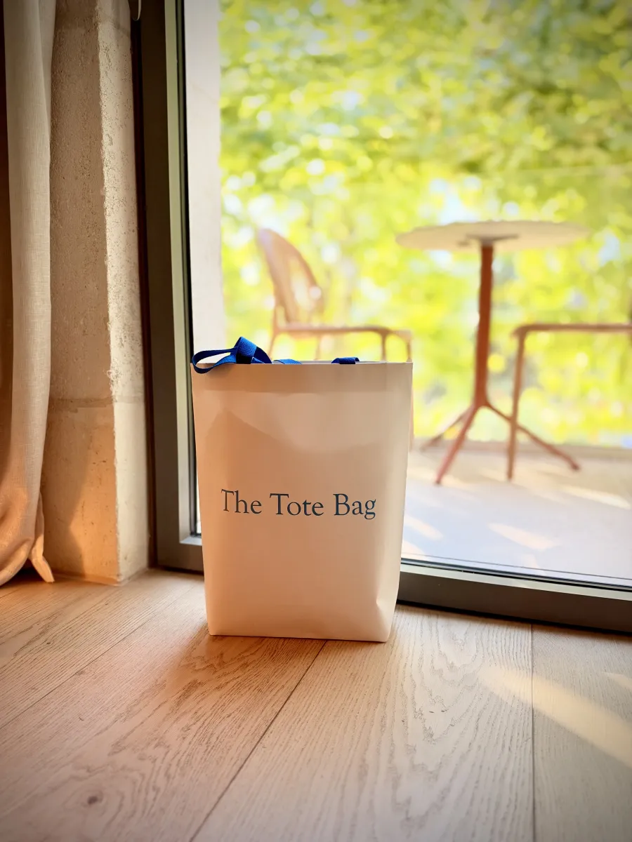 The Tote Bag debout sur un parquet, devant une porte-fenêtre ouverte