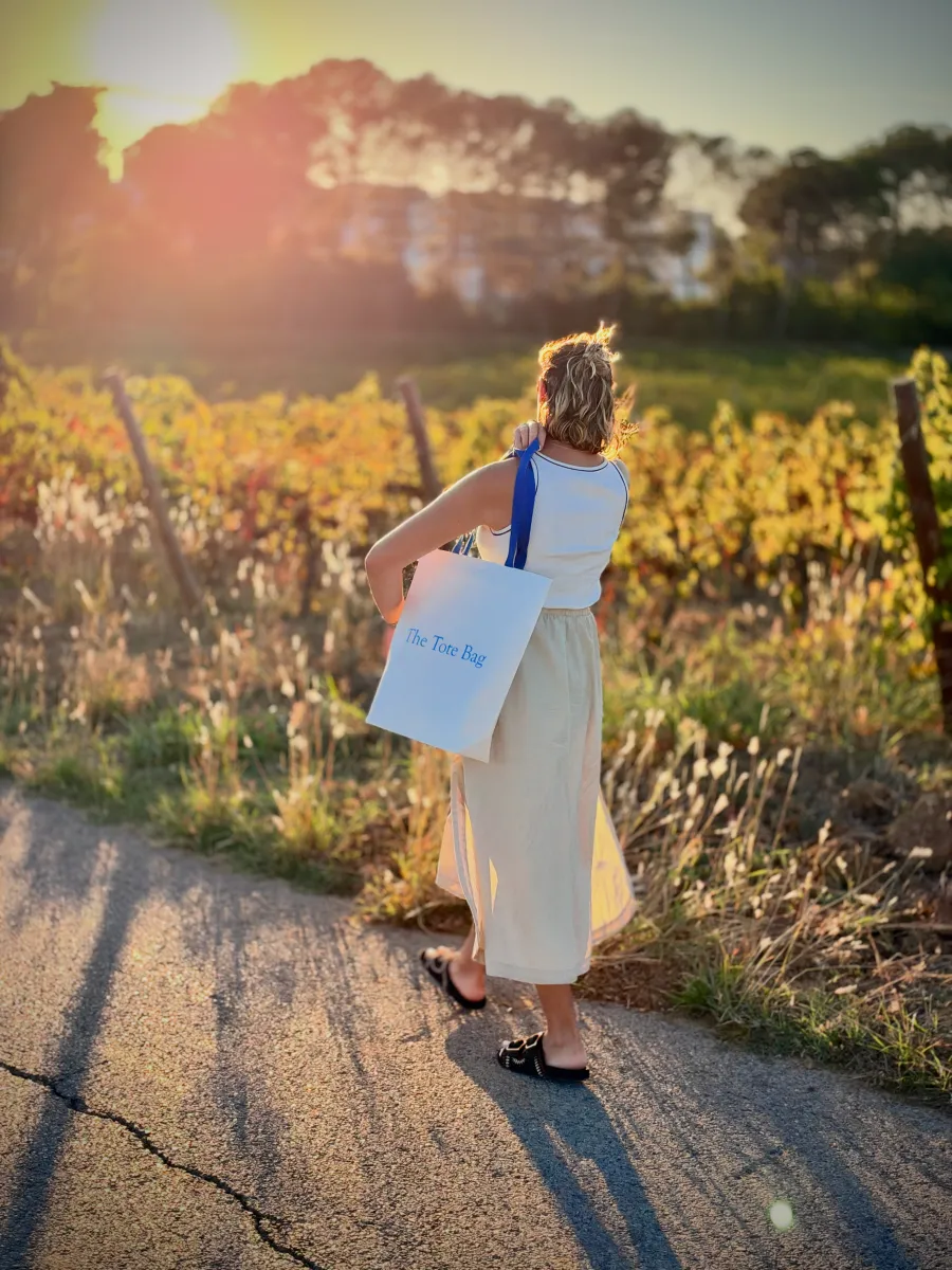 Cliente marchant au coucher du soleil dans les vignes, The Tote Bag à l'épaule